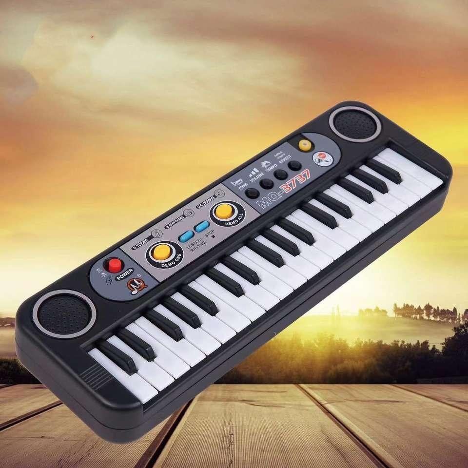 Tafeen Toys electronic toy piano keyboard with speakers, sunset background, wooden surface