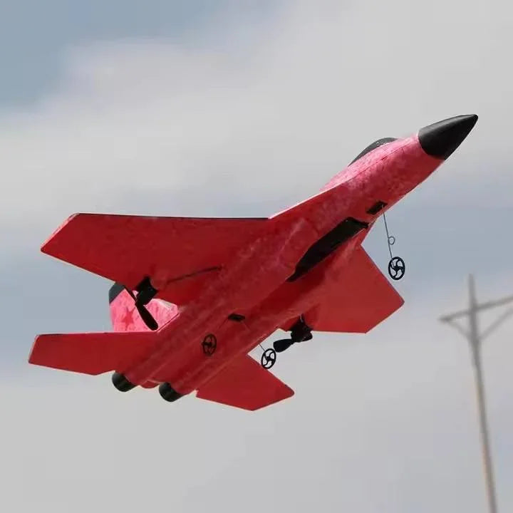 Red toy jet airplane flying outdoors, Tafeen Toys model, clear sky background